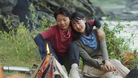 lesbian couple embracing and looking at campfire