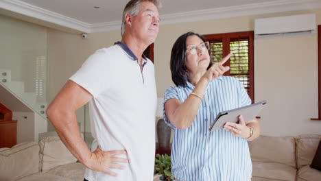 senior diverse couple discussing home renovation plans while using digital tablet
