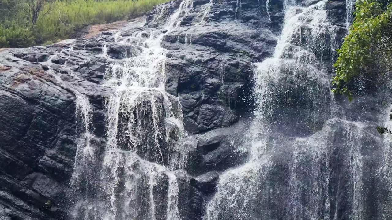 Picturesque waterfall is cascading down over dark rocks on an overcast monsoon day in the Horton Plains, Sri Lanka