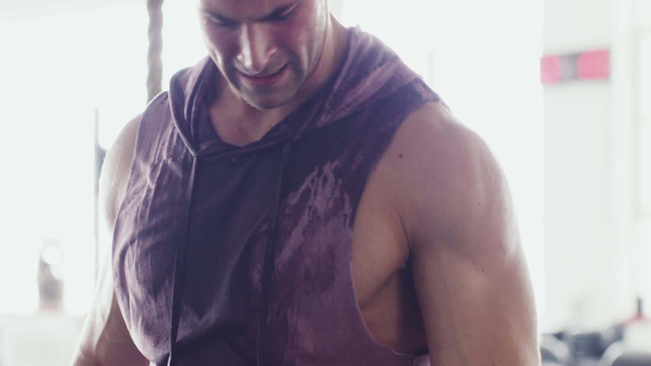 근육이 많은 젊은 남자가 팔을 흔들고 있습니다.