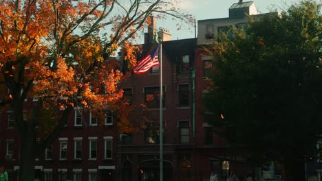 us flag in the wind in copps hill burying site at sunset with fallen leaves during fall at slow motion, boston, massachussetts, united states of america