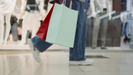 mujer sostiene bolsas de compras caminando a través del centro comercial de cerca