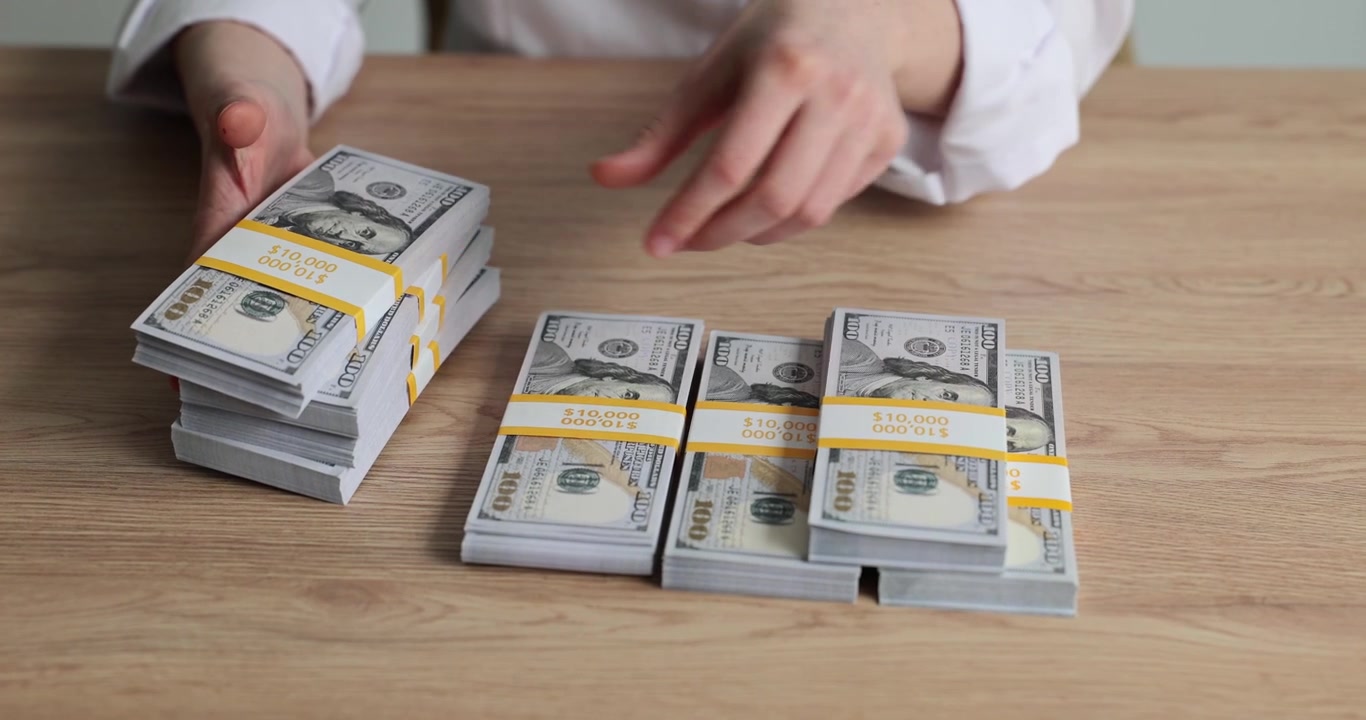 Woman hands actively count multiple large stacks of dollar bills
