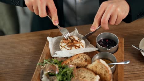 close-up of male hands cutting grilled camembert cheese