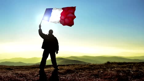 hombre silueta exitoso ganador agitando bandera francesa en la parte superior del pico de la montaña. fondo de bucle cinemagraph