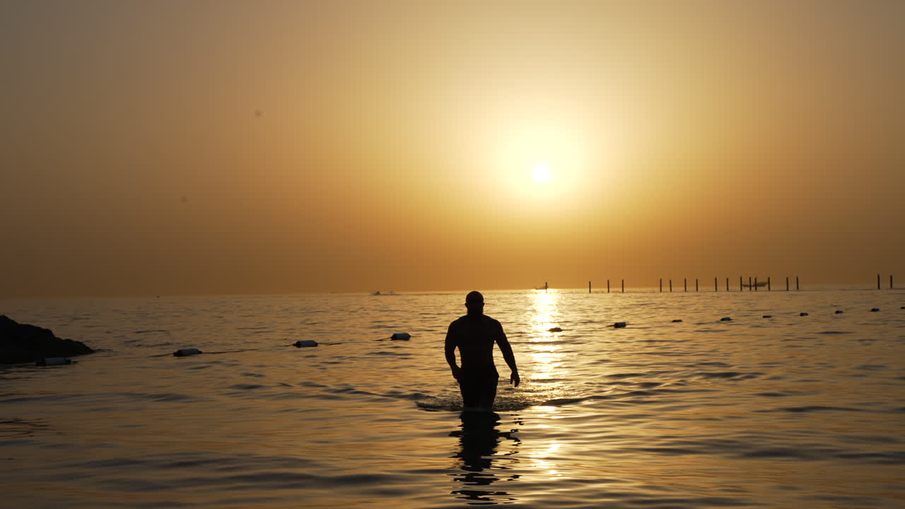 두바이 페르시아 만 일몰에서 바다에서 걷는 남자