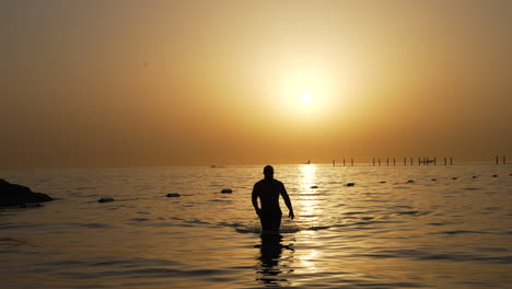 hombre saliendo del mar en dubai atardecer en el golfo pérsico