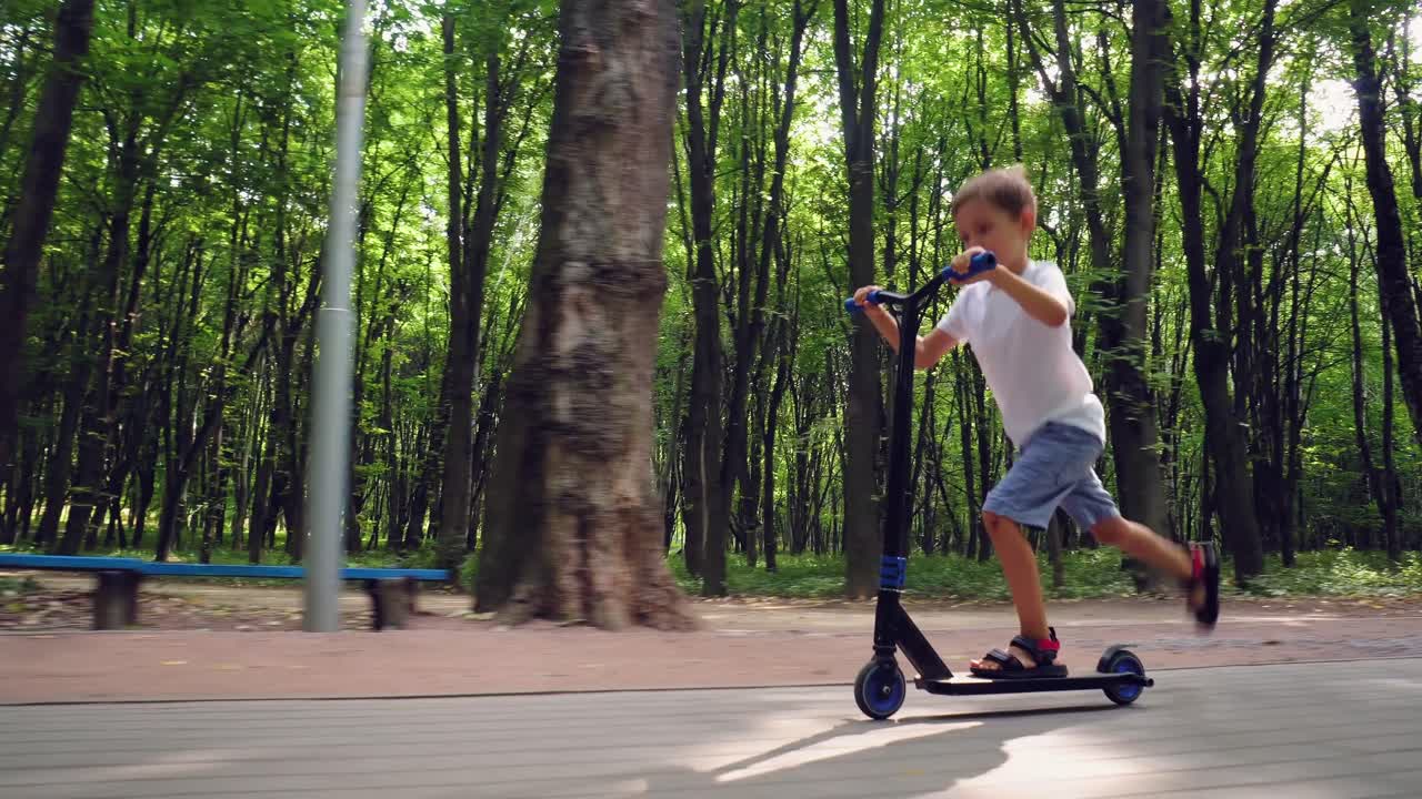 A boy rides a scooter in a city park 11
