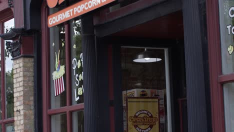 Cravings-Gourmet-Popcorn-and-Soda-Pop-Market-store-sign-in-Lansing,-Michigan-Old-Town-with-video-tilting-down