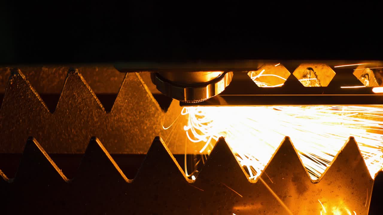 CNC laser steel cutting machine at work during darkness, close up of sparks