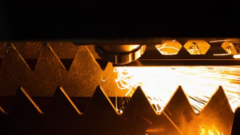 cnc laser steel cutting machine at work during darkness, close up of sparks