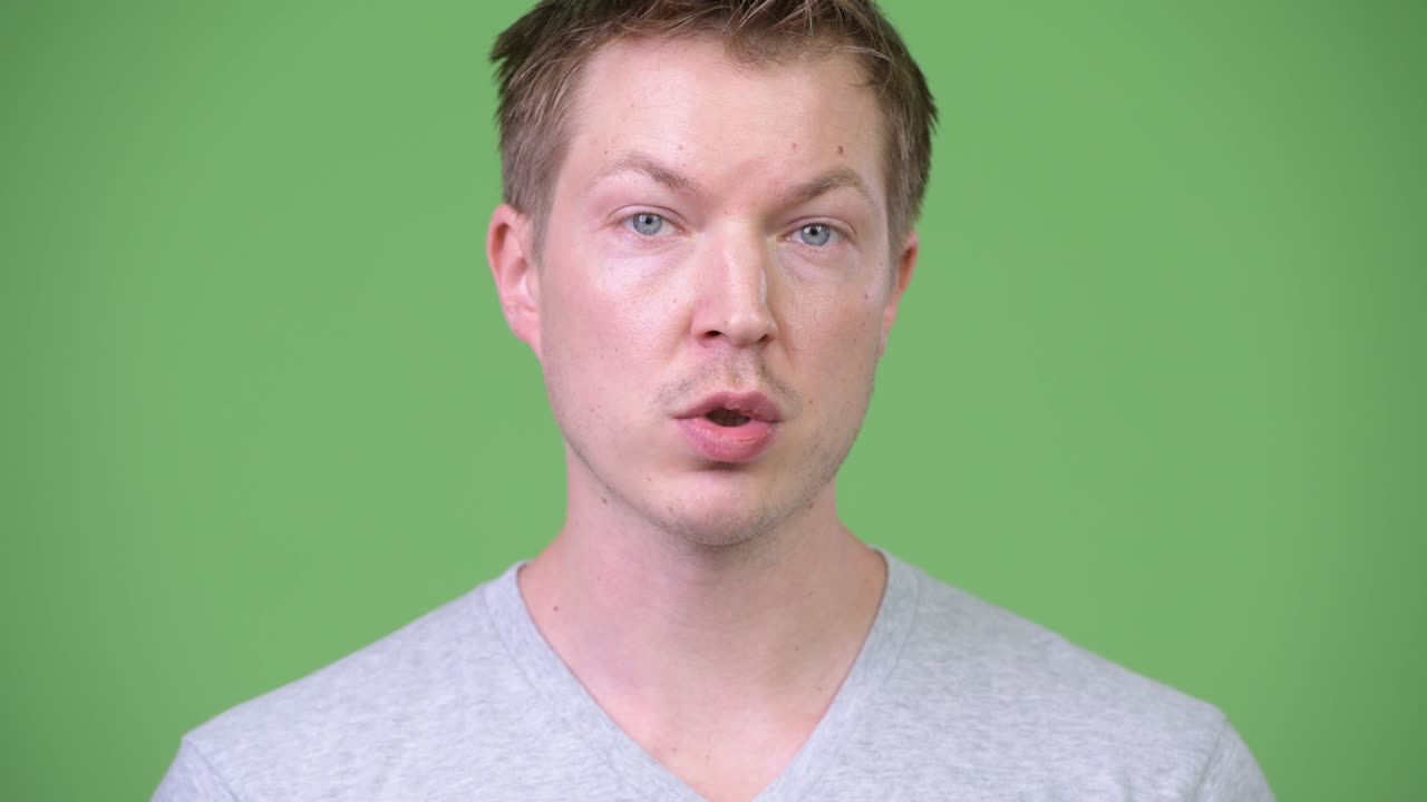 젊은 잘생긴 남자가 초록색 배경에 대해 이야기하고 있습니다.