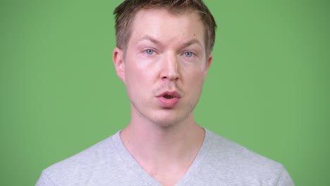 young handsome man talking against green background