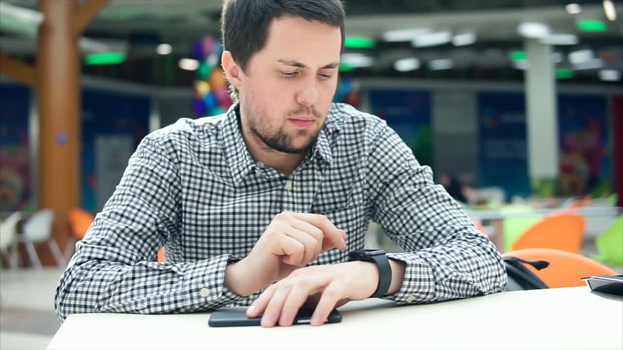 Man Checking Smartwatch in a Cafe