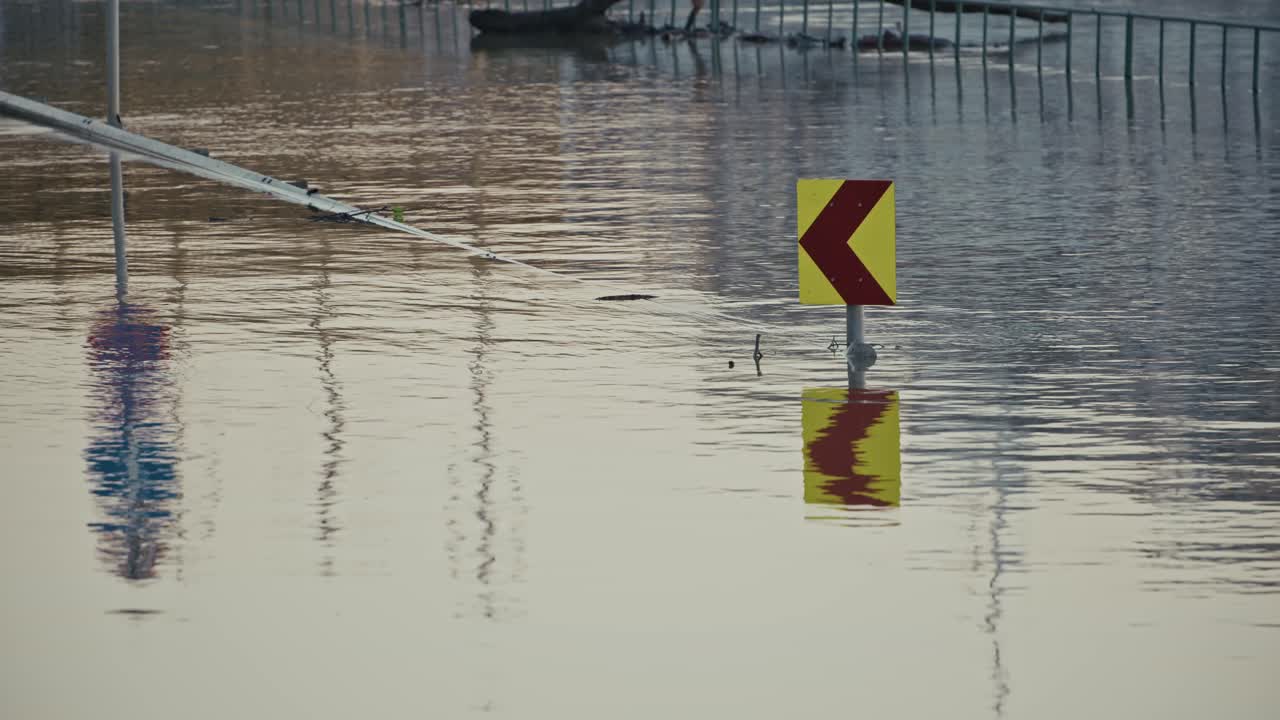Flooded road with submerged traffic signs and reflections in water during Budapest Flood of 2024