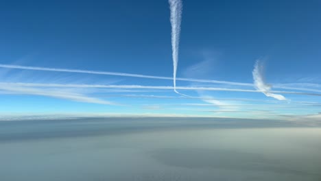 punto de vista piloto único de un cielo ajetreado lleno de estelas de chorro sobre un cielo brumoso en un cielo azul profundo temprano en la mañana