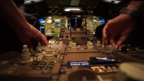 two pilots in the cockpit of a jet airplane are controlling instruments during a night flight