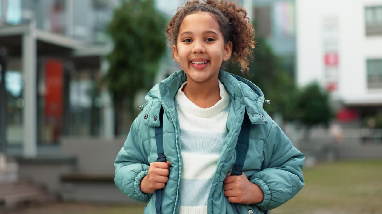 A young girl with curly hair smiling outside