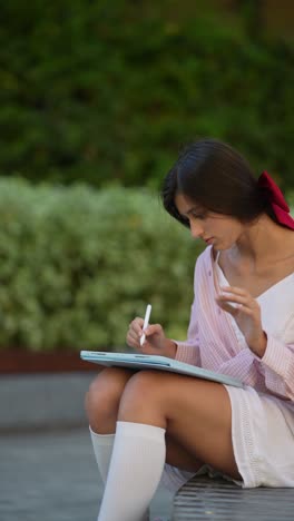 teenage girl drawing on a tablet in a park