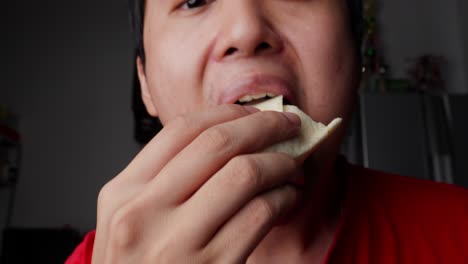 asian man eating a delicious chicken and tortilla wrap