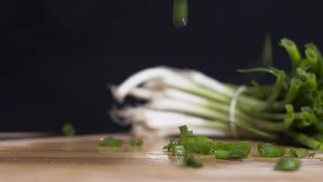Slow-motion-close-up-shot-of-chopped-spring-onions-scallions-falling-with-full-one-in-the-background