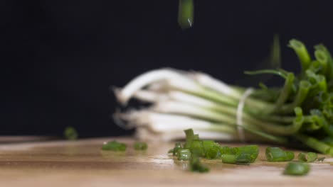 slow motion close up shot of chopped spring onions-scallions falling with full one in the background