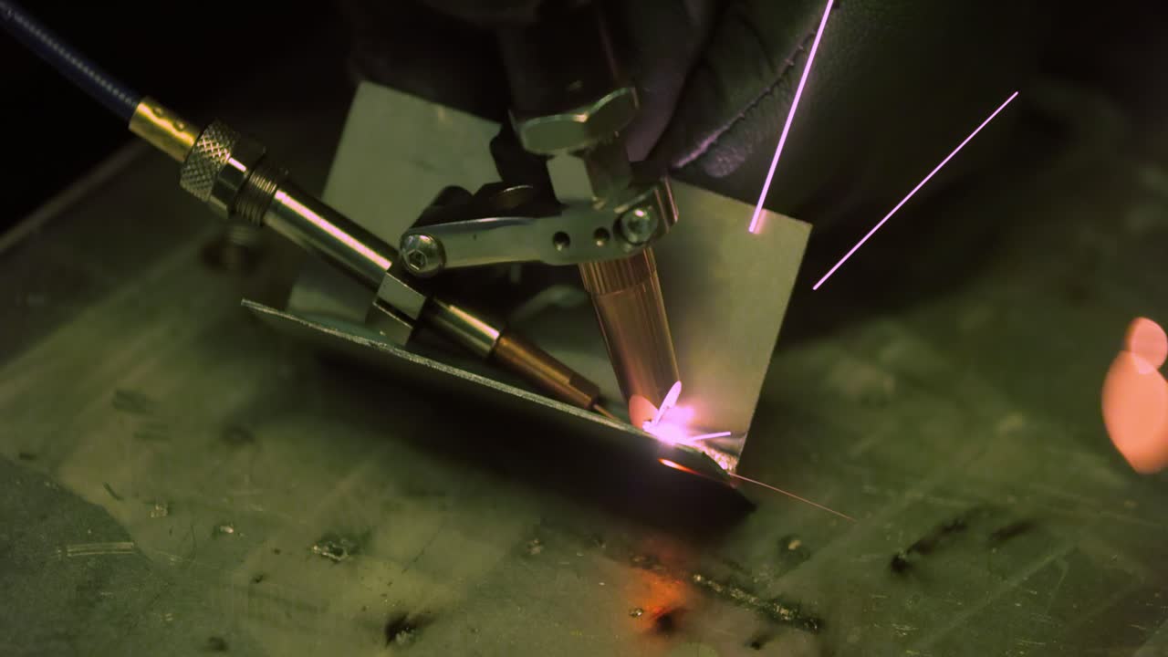 Laser welding machine with hand hold gun. Laser welding is shown in close-up.