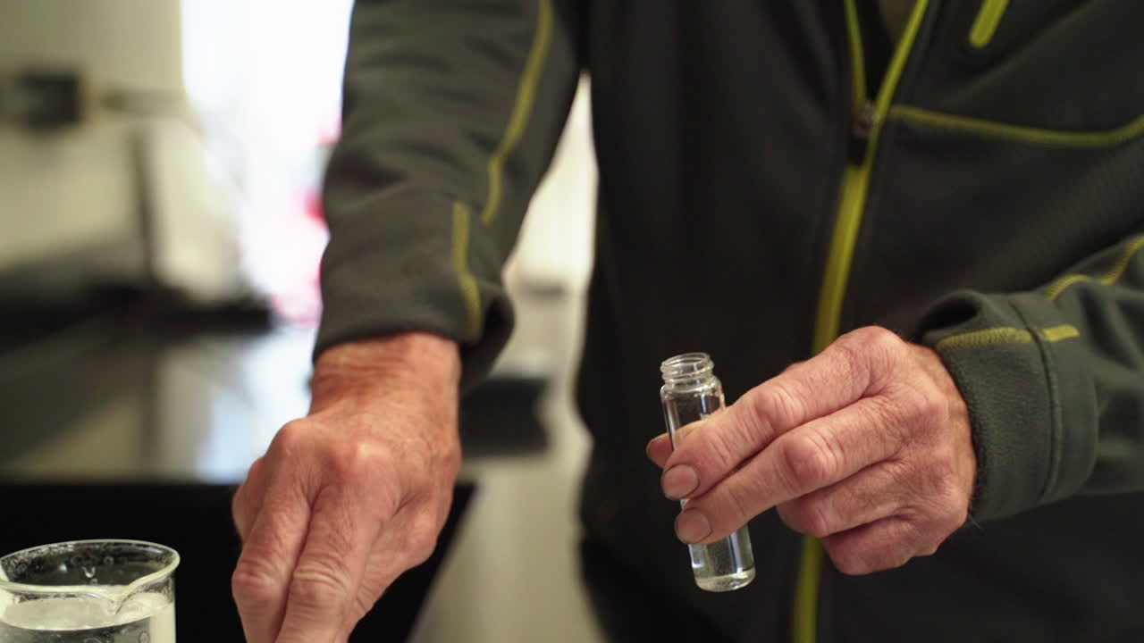 primer plano de un científico mezclando polvos químicos en un tubo de muestra en cámara lenta