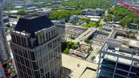 Aerial-drone-shot-very-slowly-descending-looking-past-the-Regions-Bank-tower-and-another-construction-site-onto-the-busy-highway-in-downtown-Atlanta,-Georgia-on-a-sunny-day