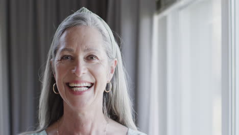 Portrait-of-middle-aged-happy-caucasian-woman-by-window-at-home-with-copy-space