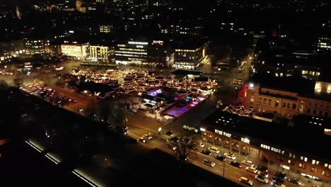 Toma-De-Drones-Del-Mercado-Navideño-En-Zúrich,-Suiza-Volando-Hacia-Atrás-Y-Revelando-El-Mercado-Por-La-Noche