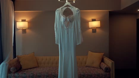 a forward smooth shot of a bridal wedding dress, hanging in a decorate room