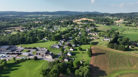 an aerial view of a small rural community surrounded by lush green fields and small forested hills