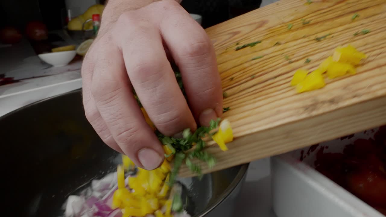 el chef prepara cebiche vertiendo pimientos y cilantro en un bol con cebollas