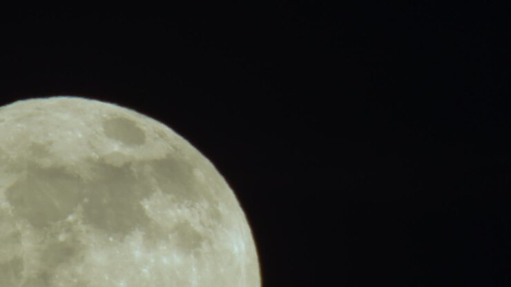 Grande plano extremo da lua cheia surgindo do canto inferior esquerdo do quadro