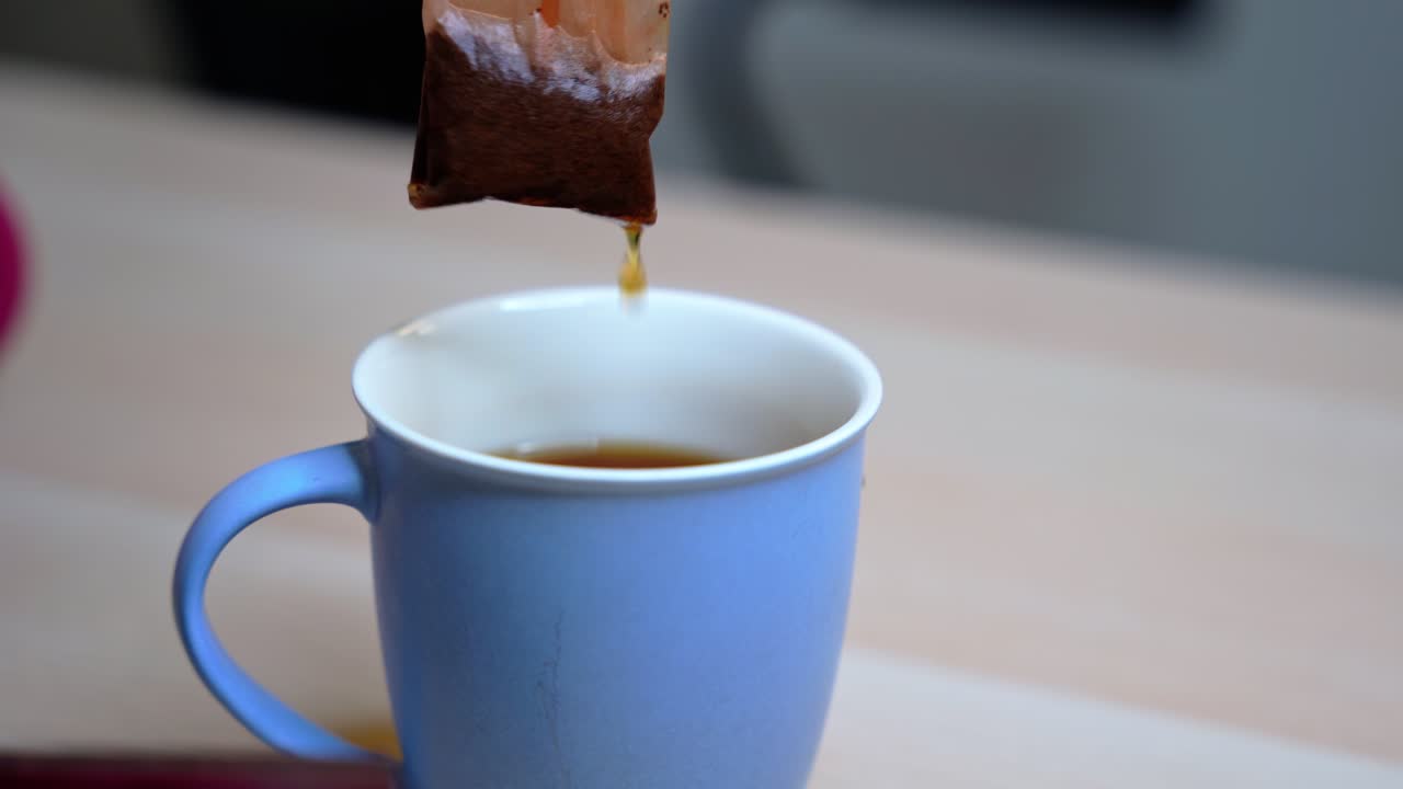 Tranquil close-up of tea bag being lifted from a hot cup—ideal for beverage, relaxation, lifestyle, mindfulness, or morning ritual visuals