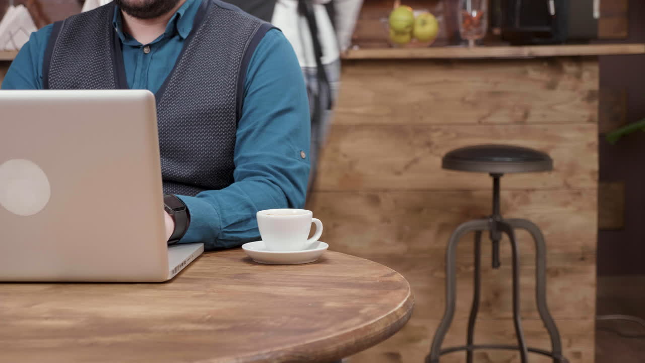 hombre trabajando en una computadora portátil en un café