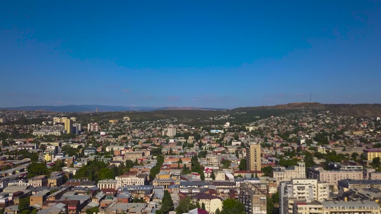 A smooth slow drone flight in a clear view under the blue sky, Tbilisi of the capital and the largest city of Georgia.