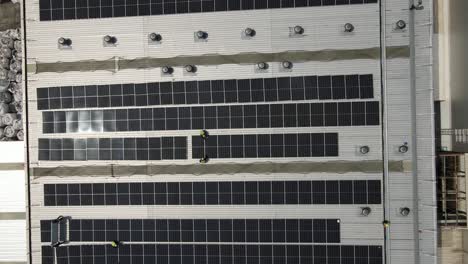 solar panels on a building roof, reflecting sunlight, symbolizing renewable energy, aerial view