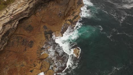 Aerial-view-moving-south-to-north-of-Maroubra-Beach-north-headland-with-unrecognisable-fisherman-on-rocks