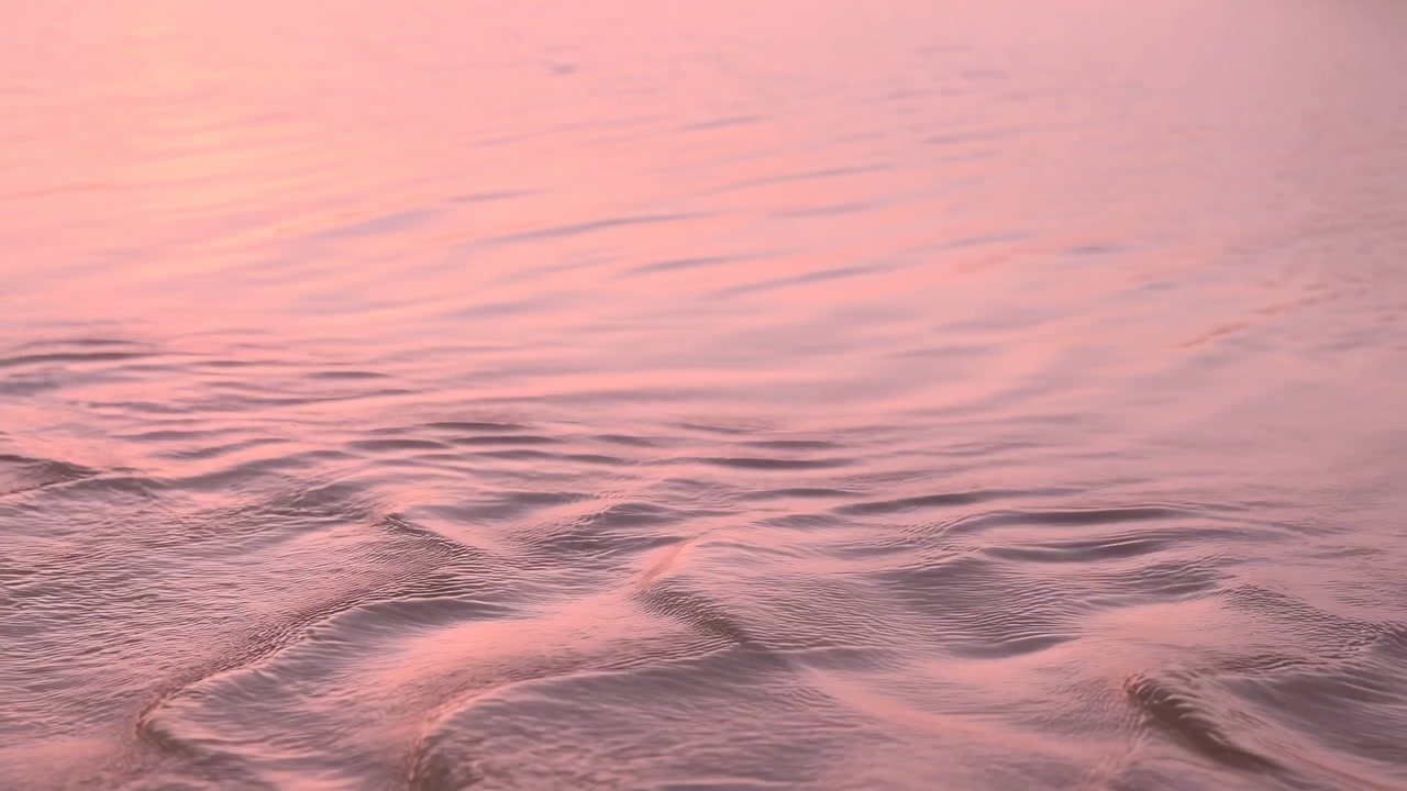 Pink Tidal Ripples Caress Sandy Shore. Gentle Evening Light Bathes Shallow Water With Soft Reflections