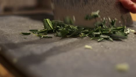 finely-chop-the-aromatics-herbs---thyme,-rosemary,-sage---close-up-footage-of-green-leaves-cutted-with-kitchen-knife