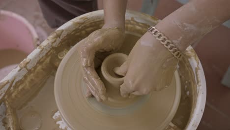 trabajador de arcilla utiliza la experiencia para lanzar hábilmente una olla de arcilla en la mesa giratoria de primer plano