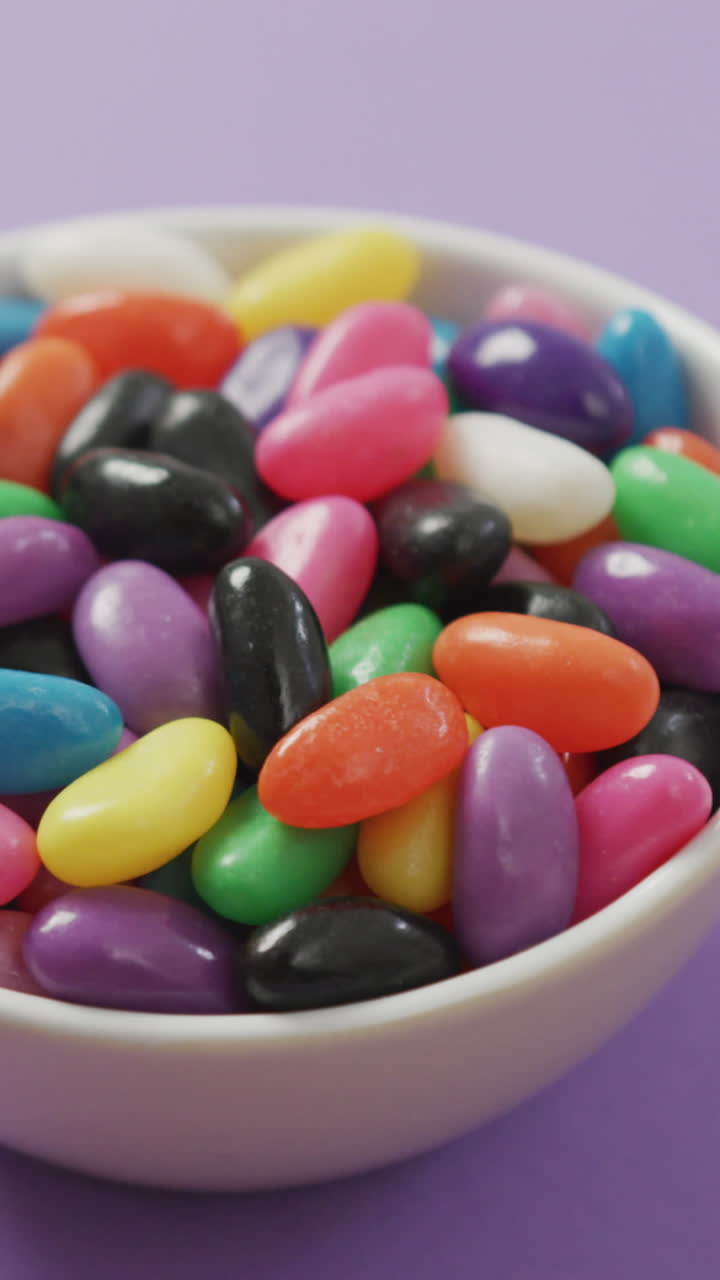video de primer plano de dulces multicolores en un cuenco sobre un fondo púrpura