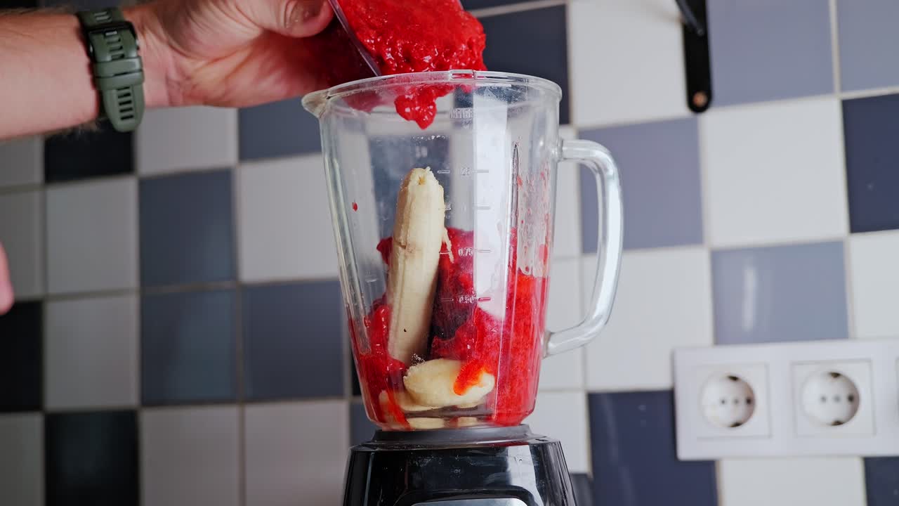 Close-up, blender filled with banana and vibrant strawberries slow kitchen scene