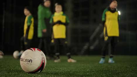 a children's football team trains at the stadium under the guidance of a coach. kids in sports uniforms practice ball exercises, improve technique, and develop teamwork on the green field