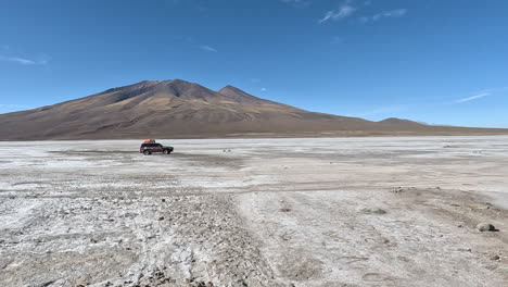 overlanding offroad car drives across dry barren salt flat in bolivia