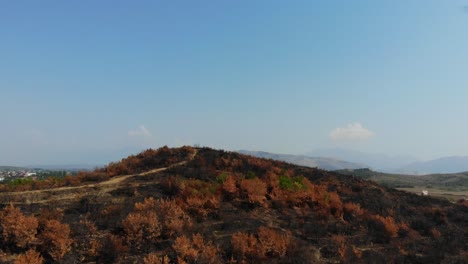 über-Einem-Verbrannten-Hügel,-Der-Nach-Einem-Massiven-Brand-Von-Schwarzer-Asche-Und-Trockenen-Bäumen-Bedeckt-War