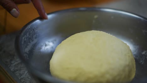 dedo deslizándose sobre el borde del cuenco con la bola de masa levantada en el interior, filmado como un disparo en cámara lenta de cerca
