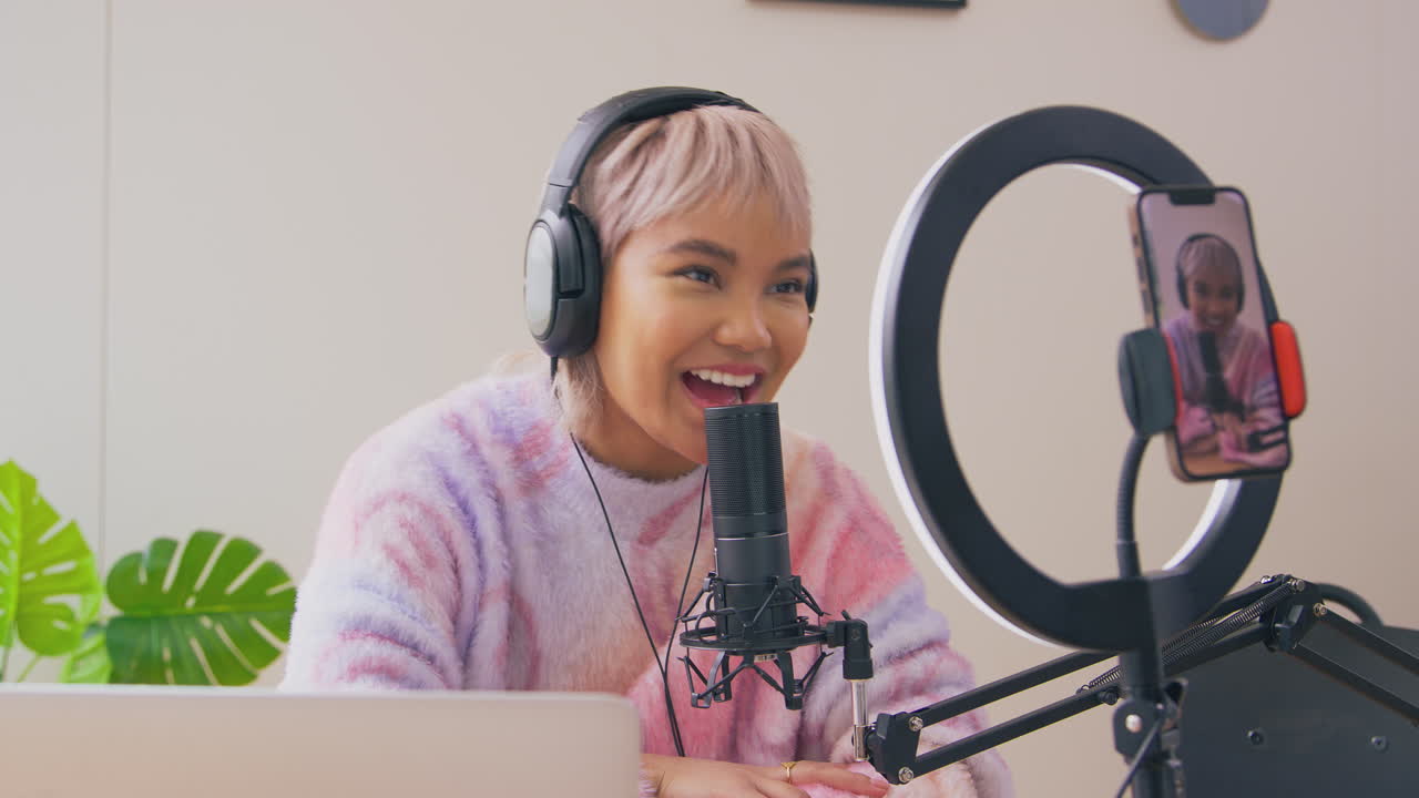vlogger femenina con auriculares con micrófono transmitiendo en vivo en el teléfono móvil